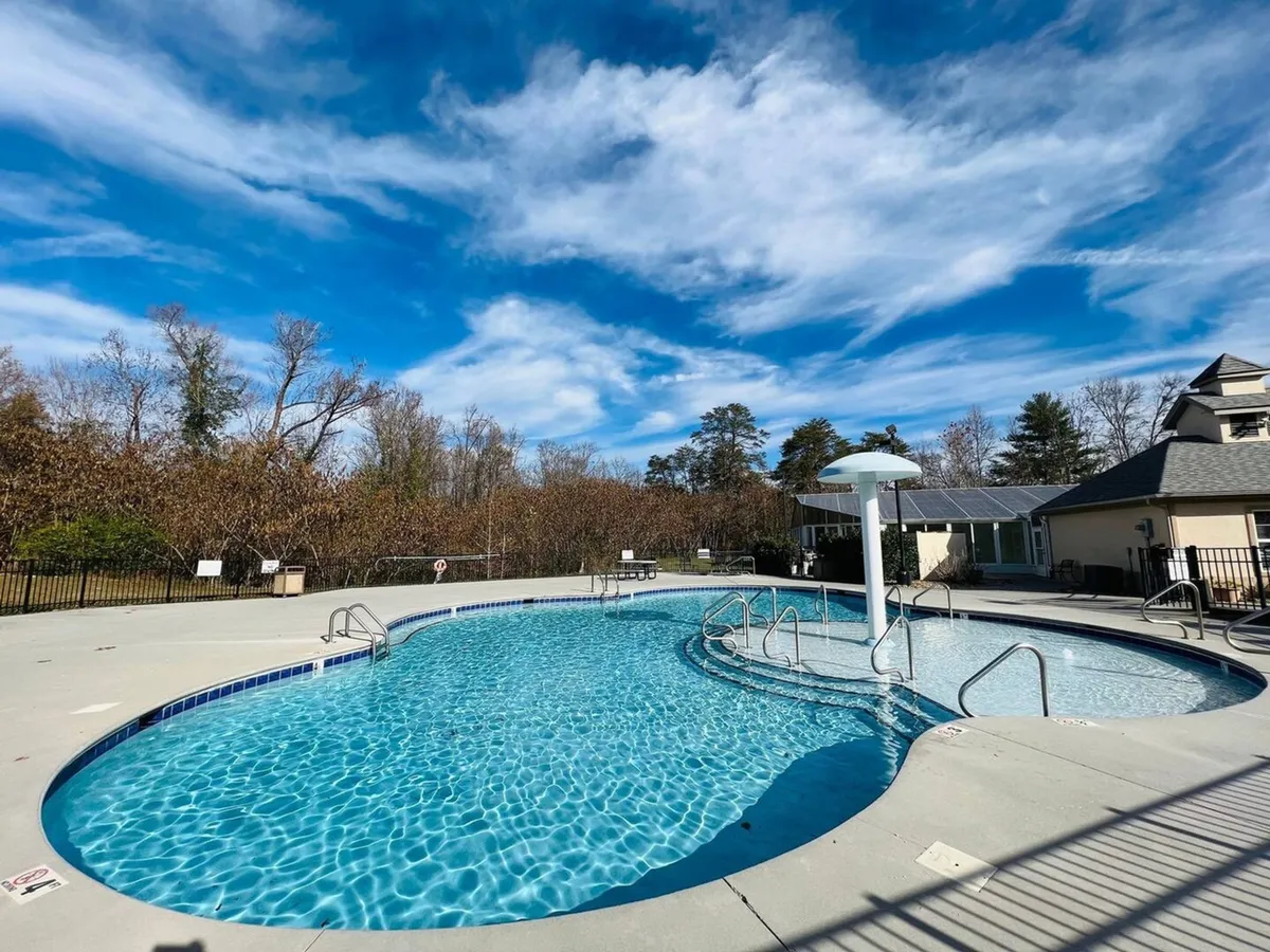 The hero image showcases a sparkling swimming pool surrounded by lush greenery, with lounge chairs inviting guests to relax. The sky is clear and sunlit, creating a tranquil and welcoming atmosphere perfect for leisurely afternoons or social gatherings.
