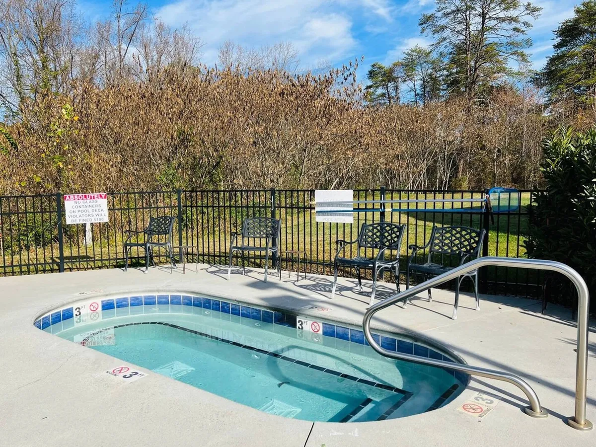 An inviting outdoor swimming pool is surrounded by lounge chairs and a tranquil natural backdrop. The setting is peaceful, perfect for sunbathing, swimming, or relaxing with friends and family.